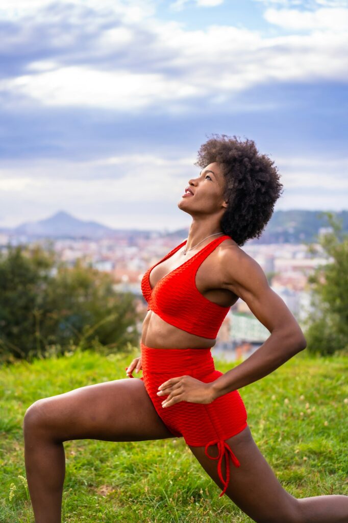 Fitness with a young black girl with afro hair, showing muscle, exercising in the field